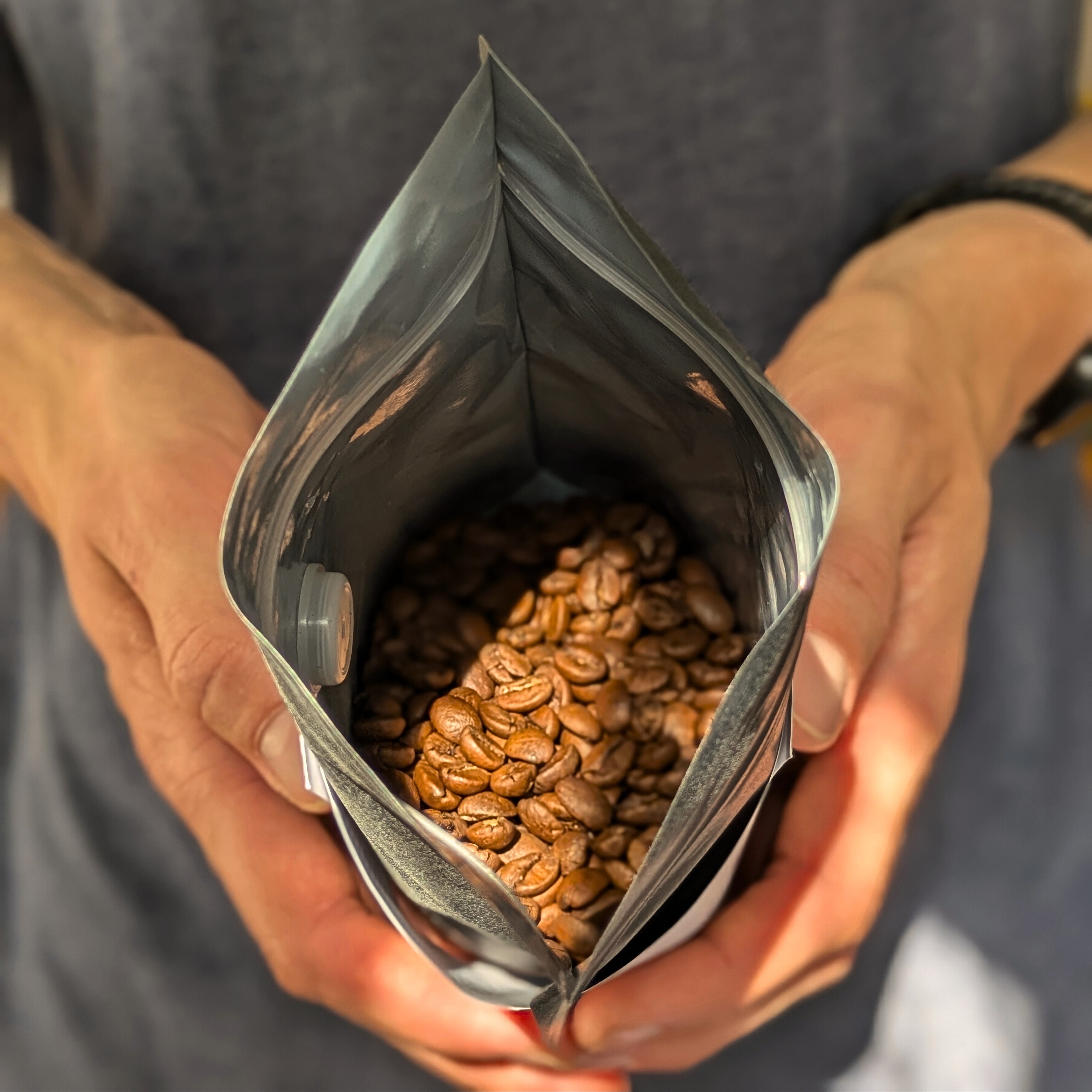 Person holding an open bag of coffee beans